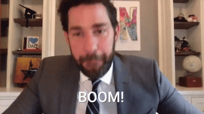 A Man In A Suit And Tie Is Sitting In Front Of A Wall With A Picture Of A Letter N On It . GIF