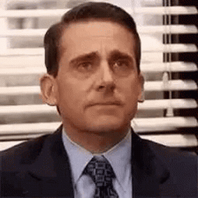 A Man In A Suit And Tie Is Sitting In Front Of A Window . GIF