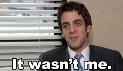 A Man In A Suit And Tie Is Sitting In Front Of A Window With Blinds . GIF