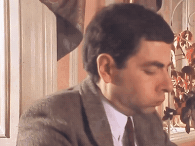 A Man In A Suit And Tie Is Sitting In Front Of A Window With His Eyes Closed . GIF