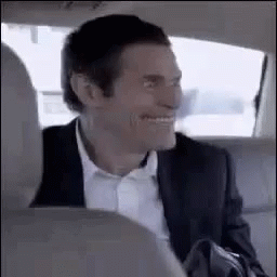 A Man In A Suit And Tie Is Sitting In The Back Seat Of A Car . GIF
