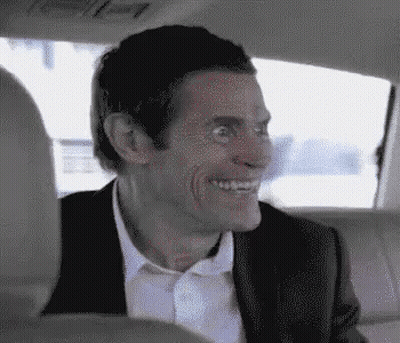A Man In A Suit And Tie Is Sitting In The Back Seat Of A Car . GIF