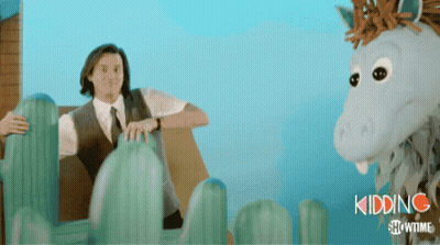 A Man In A Suit And Tie Is Sitting Next To A Stuffed Horse That Says Kidding Showtime On The Bottom GIF