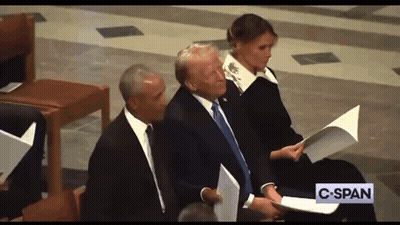 A Man In A Suit And Tie Is Sitting Next To A Woman Holding A Piece Of Paper And A Sign That Says C-Span GIF