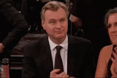 A Man In A Suit And Tie Is Sitting Next To A Woman In A Dress And Clapping . GIF