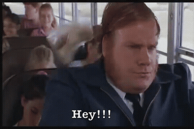 A Man In A Suit And Tie Is Sitting On A Bus And Saying Hey ! GIF