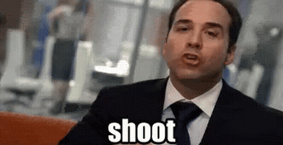 A Man In A Suit And Tie Is Sitting On A Couch And Says Shoot . GIF