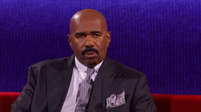 A Man In A Suit And Tie Is Sitting On A Couch GIF