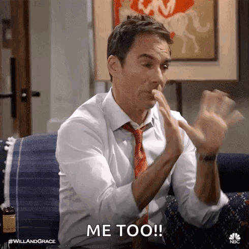 A Man In A Suit And Tie Is Sitting On A Couch Making A Funny Face And Saying `` Me Too '' . GIF