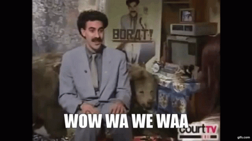 A Man In A Suit And Tie Is Sitting On A Couch With A Dog In Front Of Him . GIF