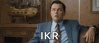 A Man In A Suit And Tie Is Sitting On A Couch With His Hands On His Knees . GIF