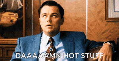 A Man In A Suit And Tie Is Sitting On A Couch With The Words Daaaaamn Hot Stuff Below Him GIF