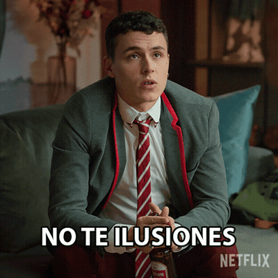 A Man In A Suit And Tie Is Sitting On A Couch With The Words No Te Ilusiones Written On The Screen GIF