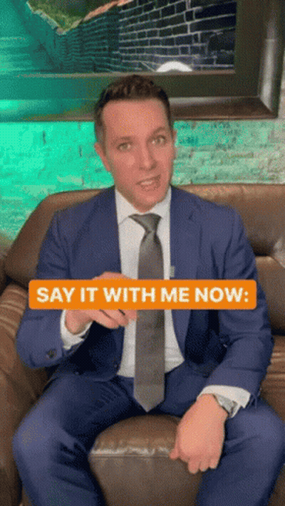 A Man In A Suit And Tie Is Sitting On A Couch With The Words Say It With Me Now GIF