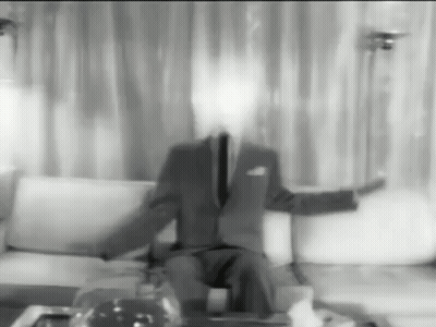 A Man In A Suit And Tie Is Sitting On A Couch Without A Face GIF