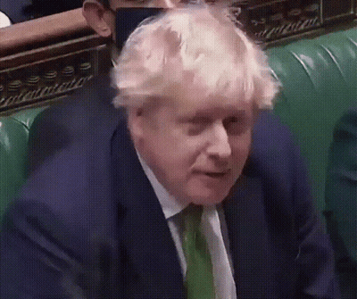 A Man In A Suit And Tie Is Sitting On A Green Chair GIF