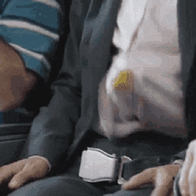 A Man In A Suit And Tie Is Sitting On A Plane GIF