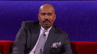 A Man In A Suit And Tie Is Sitting On A Red Couch With His Eyes Closed GIF