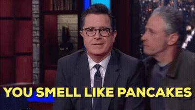 A Man In A Suit And Tie Is Sitting On A Stage And Says You Smell Like Pancakes . GIF
