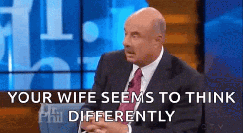 A Man In A Suit And Tie Is Sitting On A Stage And Talking To Someone . GIF