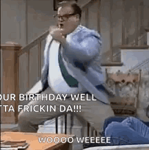 A Man In A Suit And Tie Is Sitting On A Staircase With His Fist In The Air . GIF