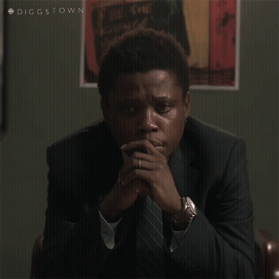 A Man In A Suit And Tie Is Sitting With His Hands Folded In Front Of A Poster That Says Diggstown GIF