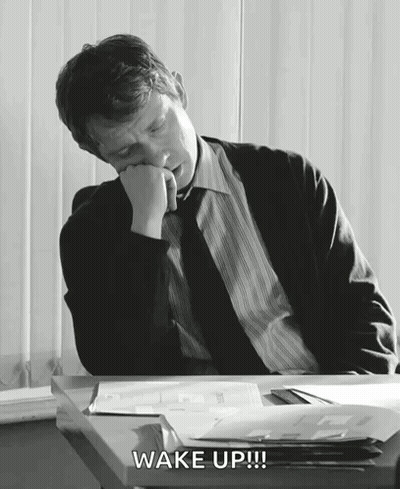 A Man In A Suit And Tie Is Sleeping At A Desk And The Words Wake Up Are Above Him GIF