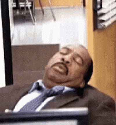 A Man In A Suit And Tie Is Sleeping With His Eyes Closed . GIF