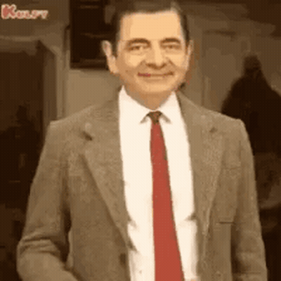 A Man In A Suit And Tie Is Smiling . GIF