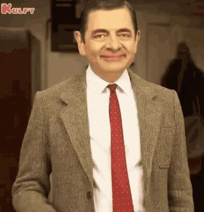 A Man In A Suit And Tie Is Smiling . GIF