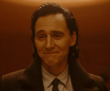 A Man In A Suit And Tie Is Smiling And Looking At The Camera GIF