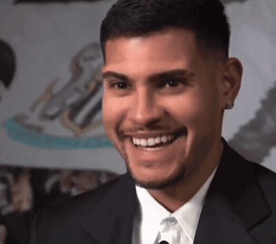 A Man In A Suit And Tie Is Smiling And Looking To The Side GIF