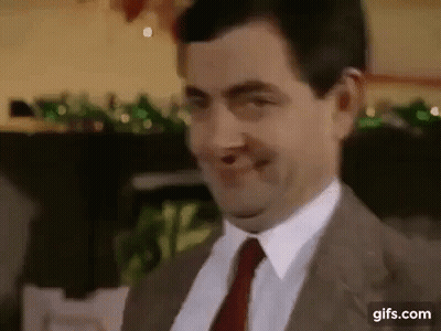 A Man In A Suit And Tie Is Smiling And Making A Funny Face . GIF