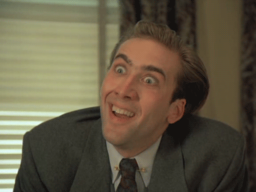 A Man In A Suit And Tie Is Smiling And Making A Funny Face GIF