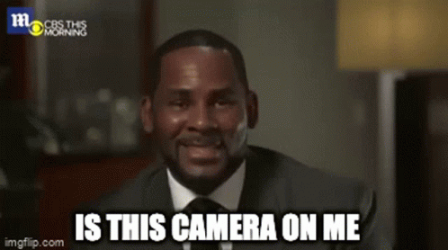 A Man In A Suit And Tie Is Smiling And Saying " Is This Camera On Me " GIF