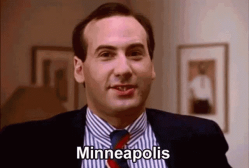 A Man In A Suit And Tie Is Smiling And Saying Minneapolis GIF
