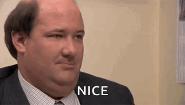 A Man In A Suit And Tie Is Smiling And Saying Nice . GIF