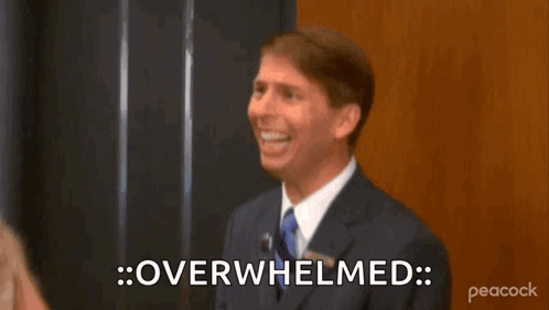A Man In A Suit And Tie Is Smiling And Saying Overhelmed . GIF