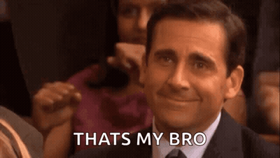 A Man In A Suit And Tie Is Smiling And Saying `` That 'S My Bro '' While Sitting In A Crowd . GIF