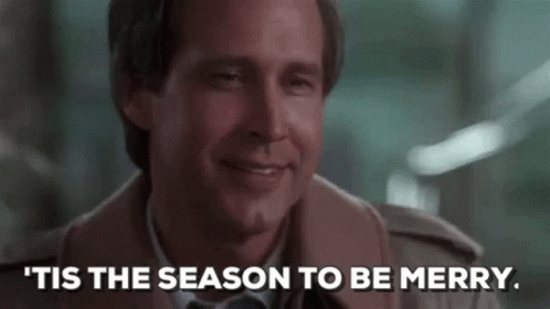 A Man In A Suit And Tie Is Smiling And Says `` Tis The Season To Be Merry . '' GIF