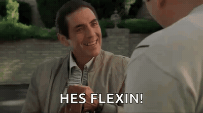 A Man In A Suit And Tie Is Smiling And Talking To Another Man While Sitting At A Table . GIF