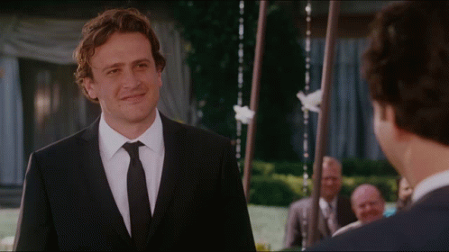 A Man In A Suit And Tie Is Smiling At Another Man GIF