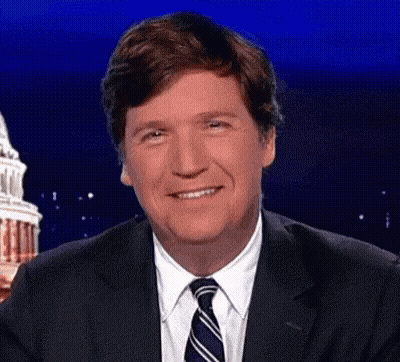 A Man In A Suit And Tie Is Smiling In Front Of A Building . GIF