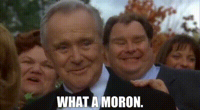 A Man In A Suit And Tie Is Smiling In Front Of A Group Of People . GIF