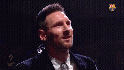 A Man In A Suit And Tie Is Smiling In Front Of A Sign That Says Ballon Dor GIF