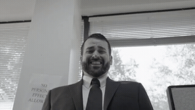 A Man In A Suit And Tie Is Smiling In Front Of A Sign That Says No Person Effect Allow GIF