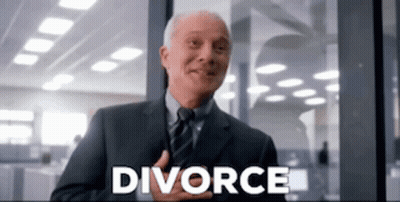 A Man In A Suit And Tie Is Smiling In Front Of A Window With The Word Divorce Written On It . GIF