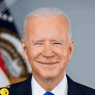 A Man In A Suit And Tie Is Smiling In Front Of An American Flag . GIF