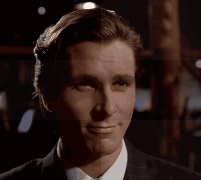 A Man In A Suit And Tie Is Smiling In The Dark GIF