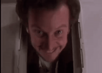 a man in a suit and tie is smiling while looking out of a hole in the wall .